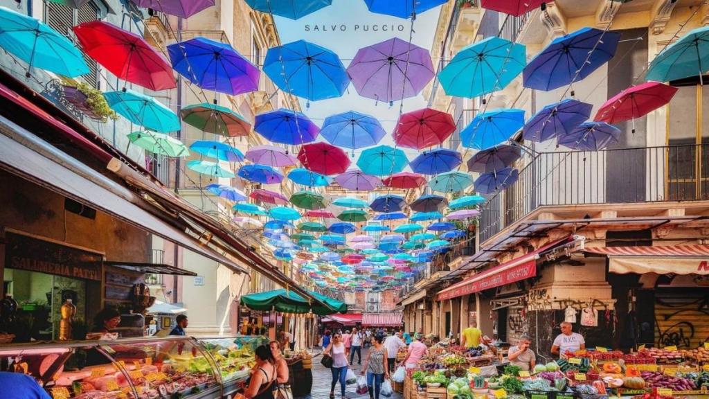 Colorful umbrellas on the streets of the historic fish market in Catania. ®greenme.it